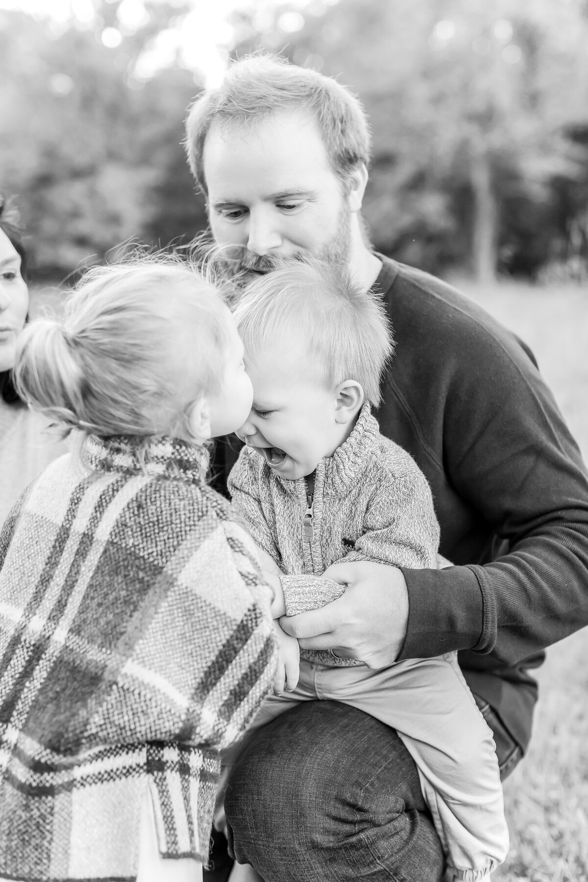 A washington dc family photographer photo of a toddler boy being kissed by his older sister