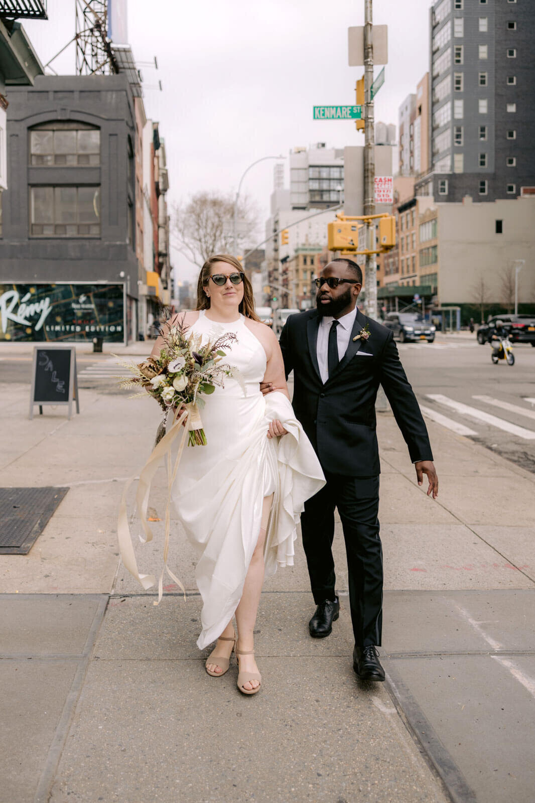 The bride and the groom are walking at Kenmare Street, New York City.