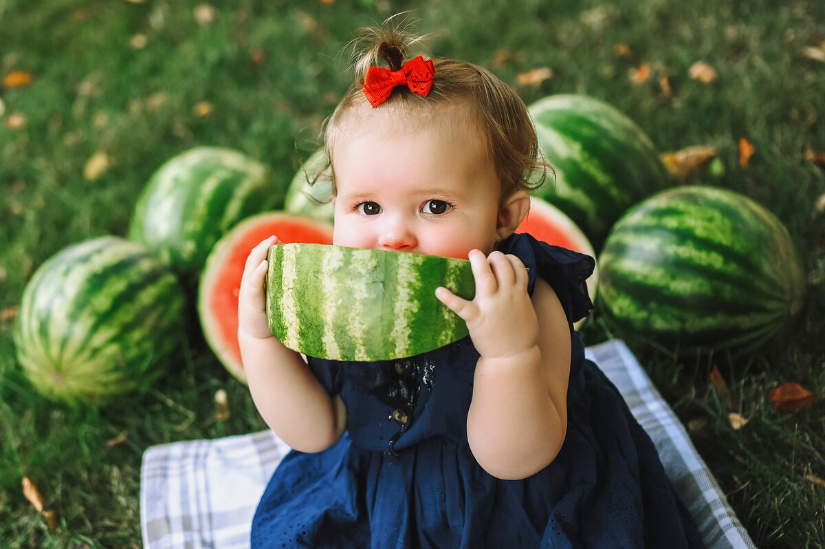 Baby takes a big bite of a slice of watermelon