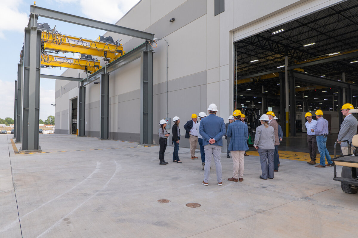 A group of people in hard hats standing outside a warehouse 