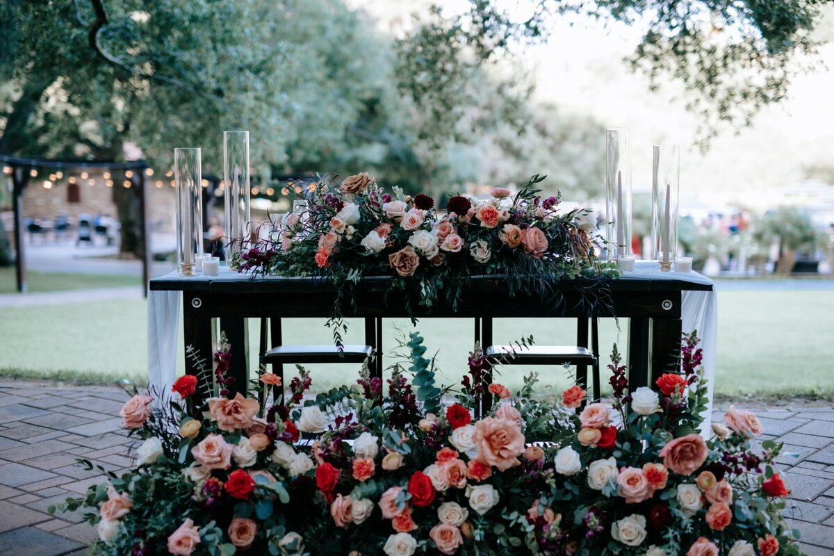 The gorgeous wedding table for the Bride and Groom at the reception covered in flowers on top of the table and around the bottom.
