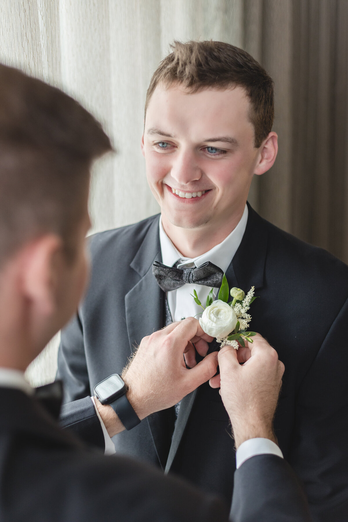 Best Man pins boutonniere on groom