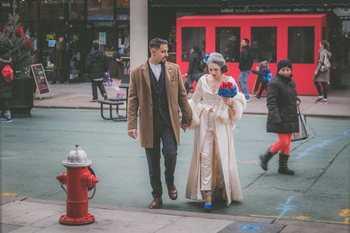 Bride and groom walk on Jersey City street.
