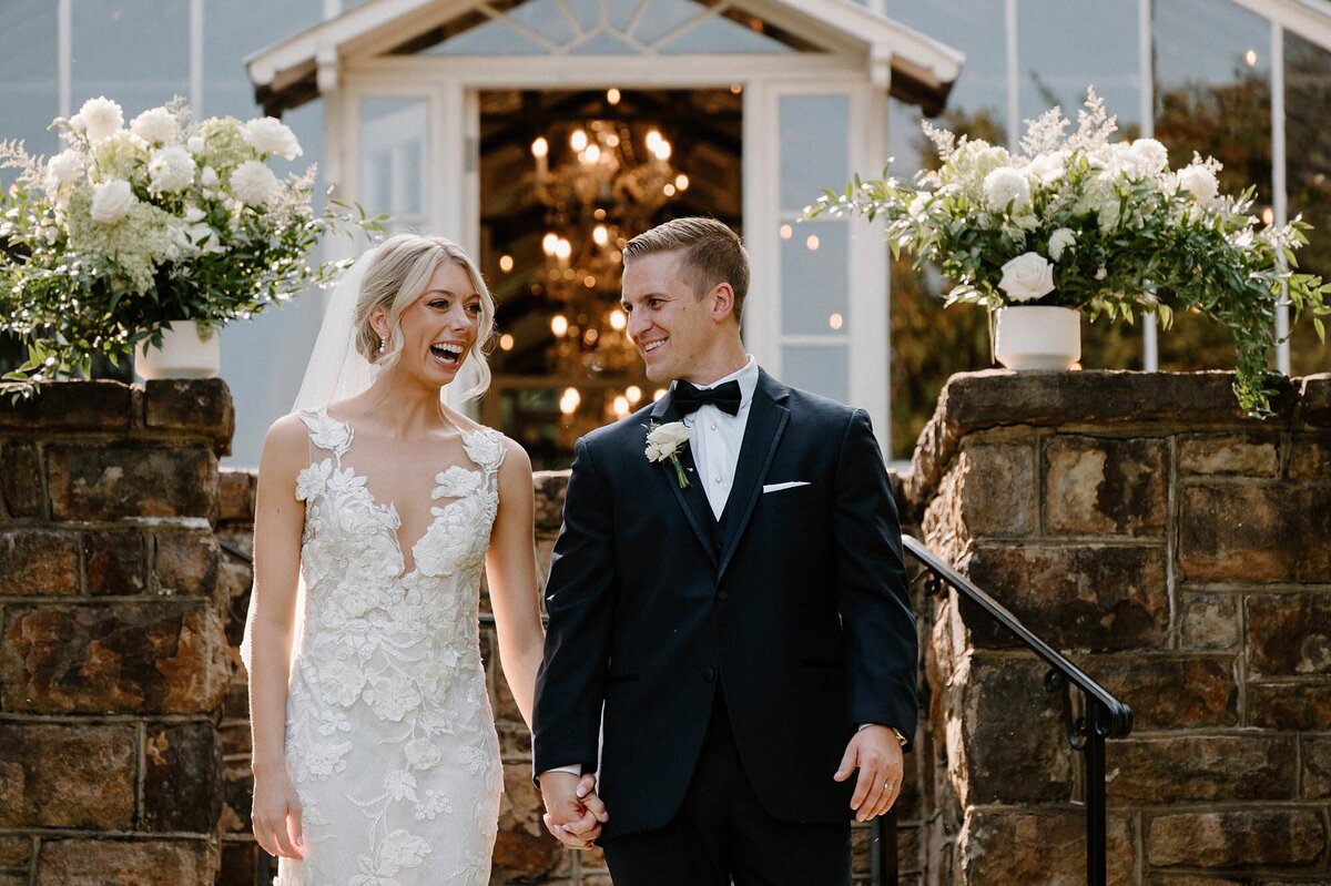 A wedding couple holding hands and laughing together 