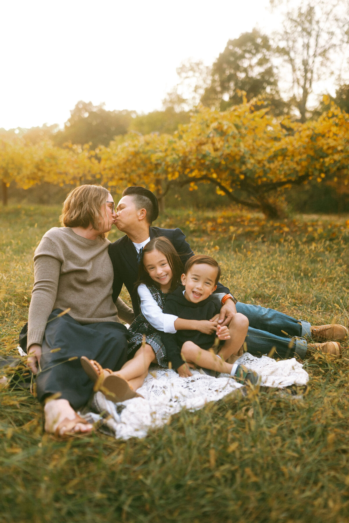 A family sitting on a blanket with the golden leaves behind them at Hyde Farm Park. 