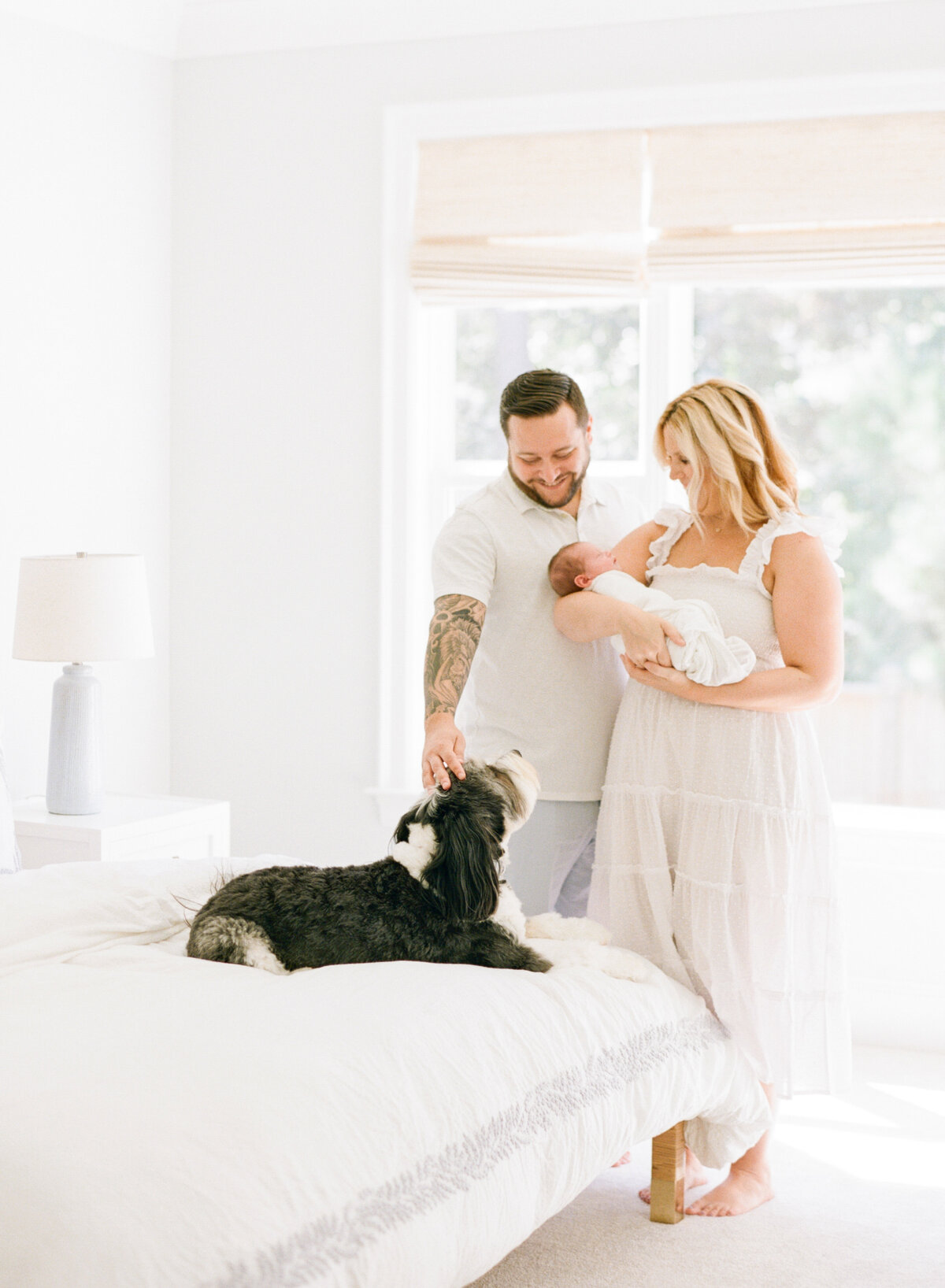 Family pets their puppy as they hold their newborn son. Image by Raleigh newborn photographer A.J. Dunlap Photography.