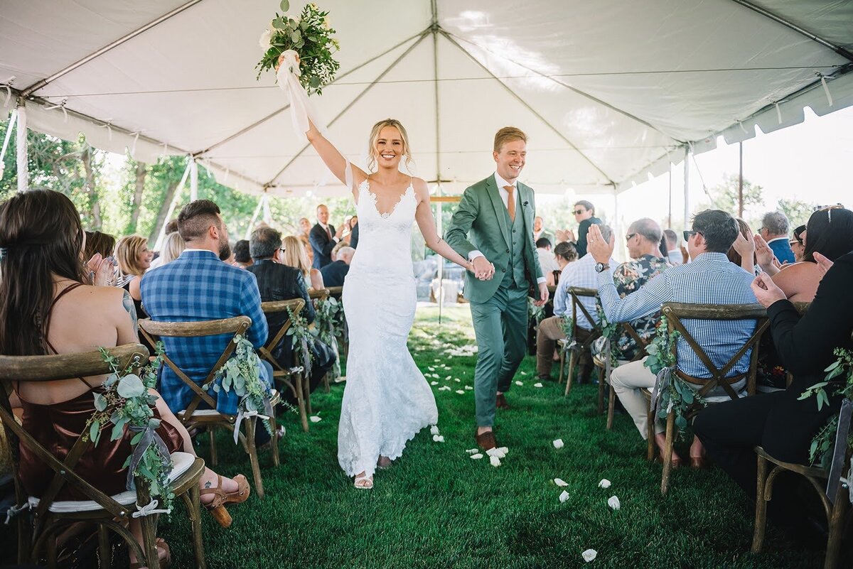 Bride and groom celebrate after their wedding ceremony exiting the aisle.