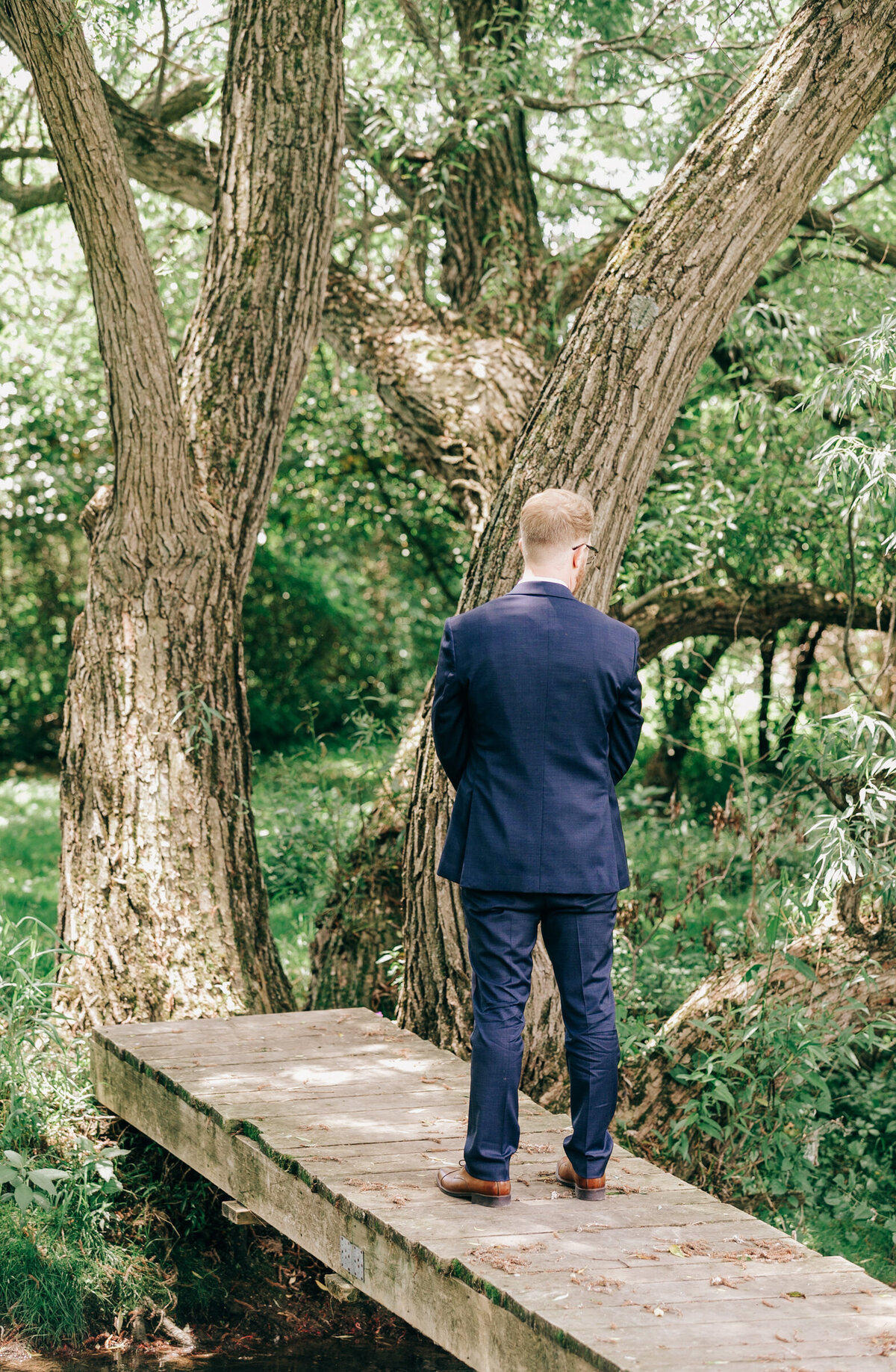Groom patiently waiting for gorgeous bride during their first look
