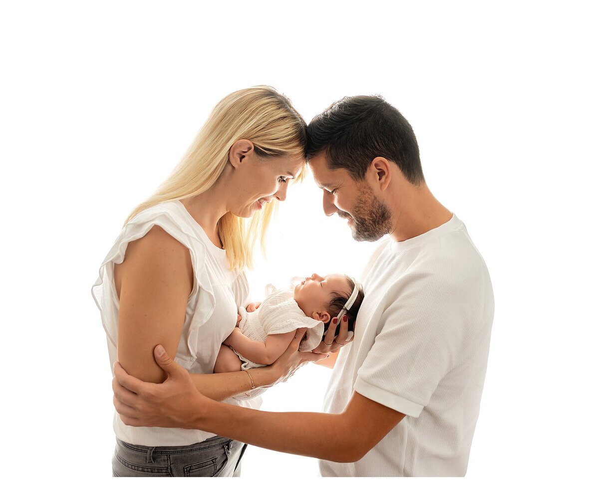 parents holding baby and looking down admiring baby