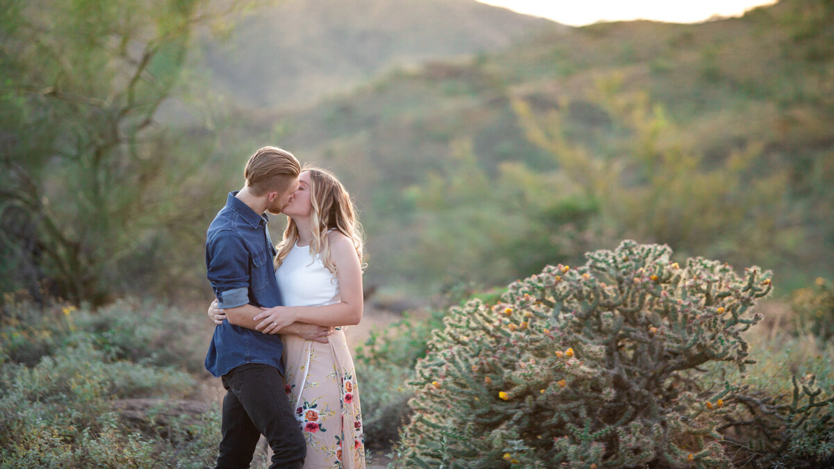 engaged couple kissing in desert