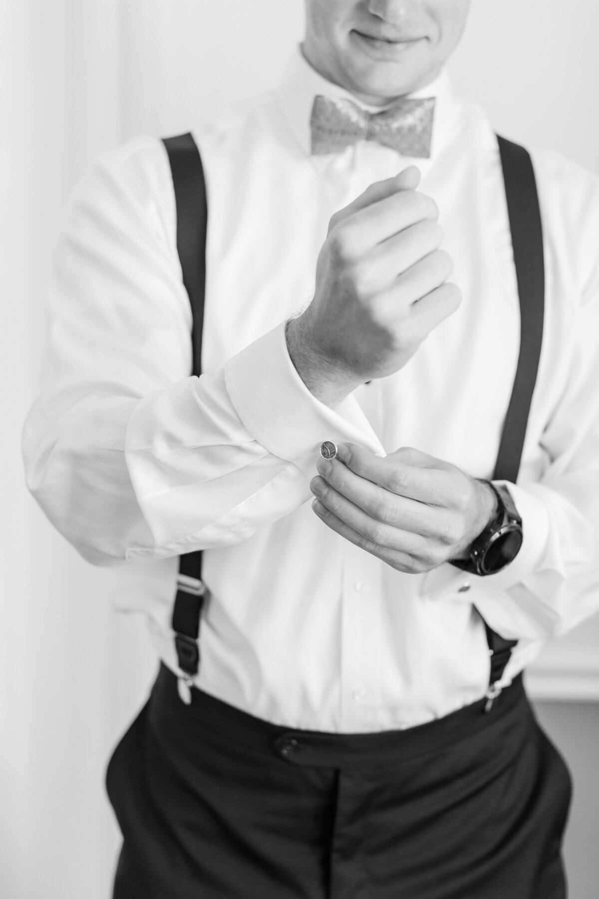 Up close of groom putting o n cuff links.