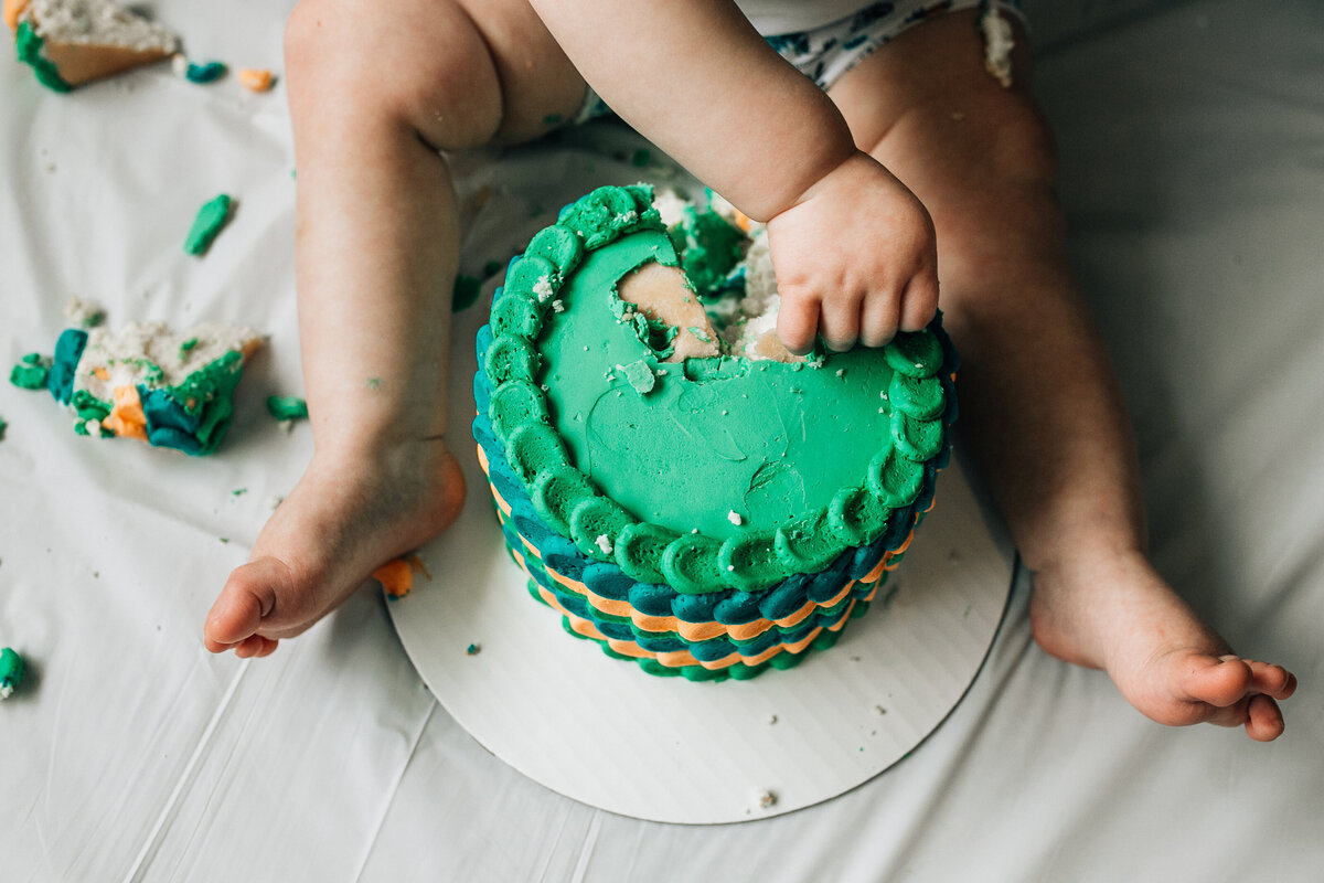 Baby sits on the floor with cake.