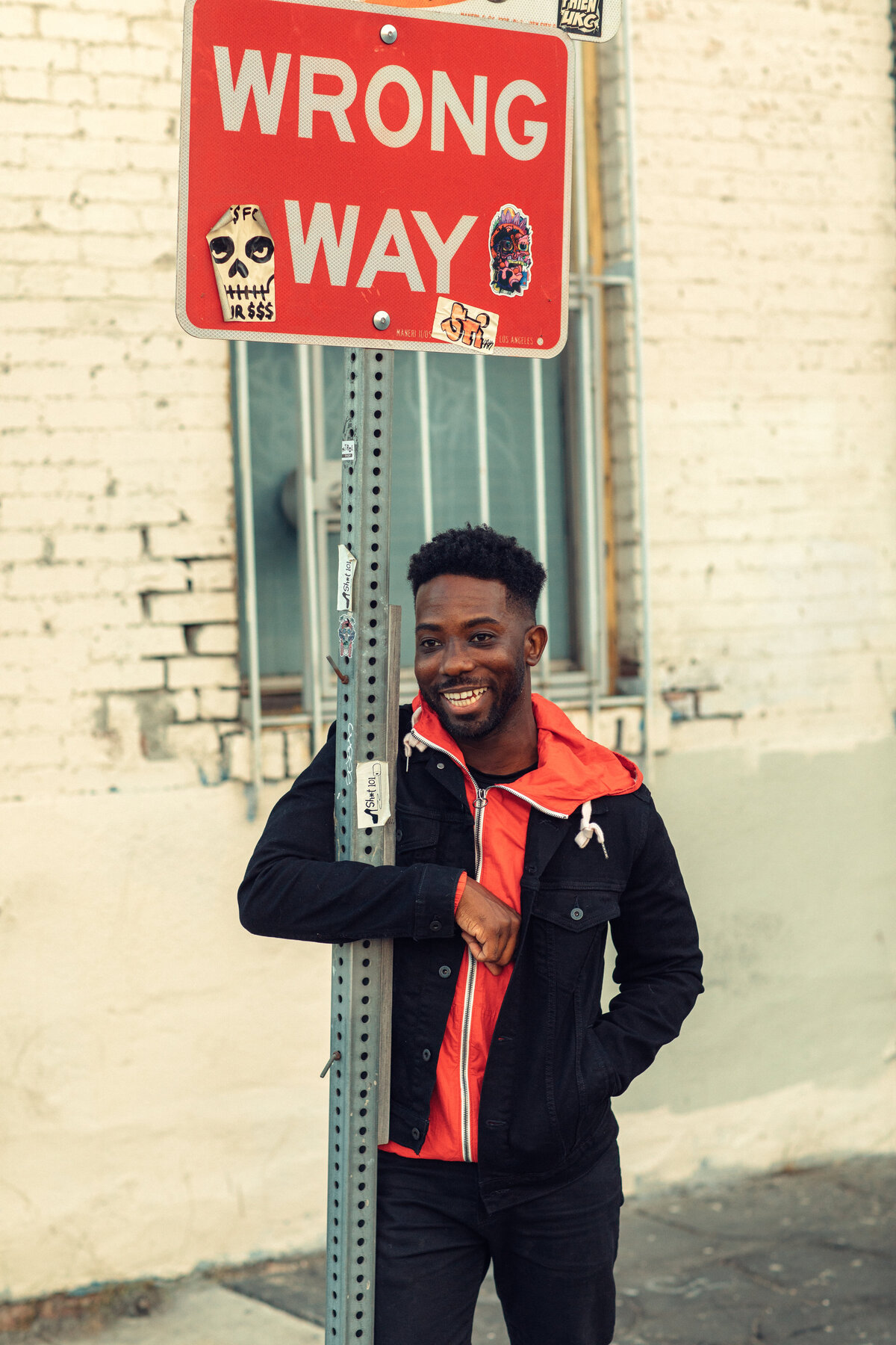 Portrait Photo Of Young Black Man Hugging a Road Signage Los Angeles