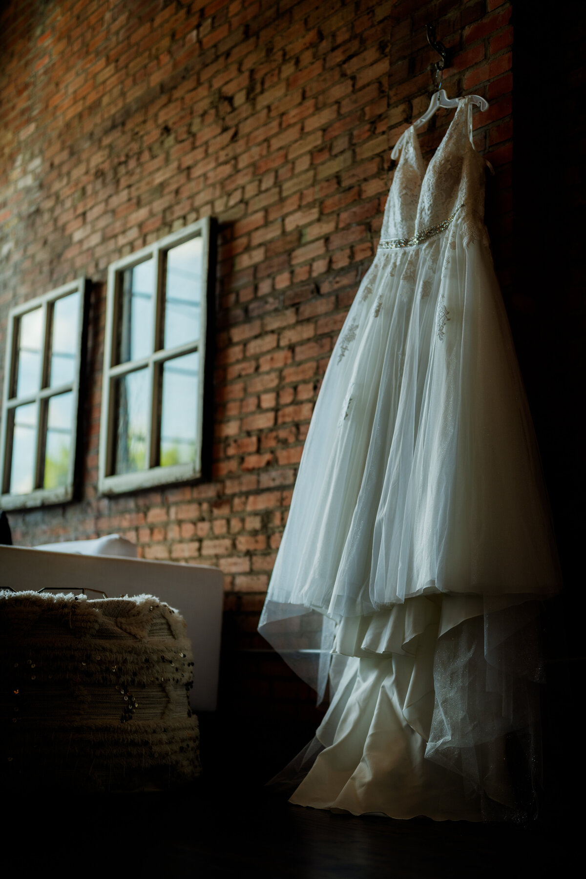 A dramatic shot of a wedding dress hanging against a brick wall, capturing the venue’s industrial-chic aesthetic in Dallas.