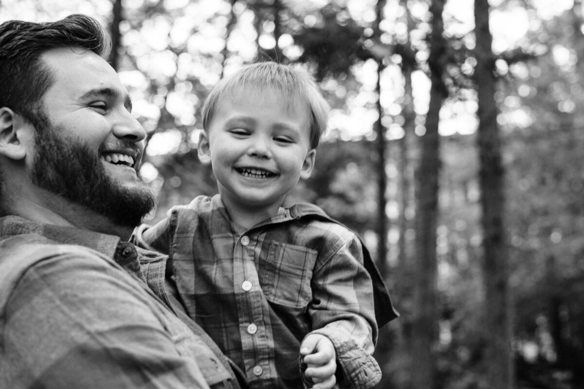 Father and son laughing in the forest.
