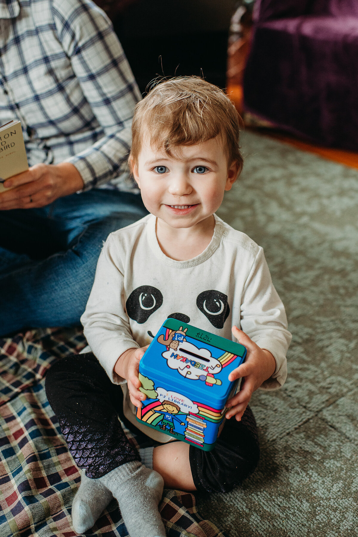 little girl holding money box smiles into camera
