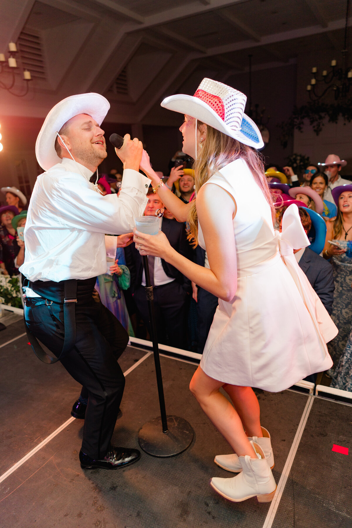 Bride and groom closed the night with a live sing along of "Revival" by Zach Bryan. Bride and groom on stage singing into microphone. Fun, candid wedding reception photos. Kailee DiMeglio Photography