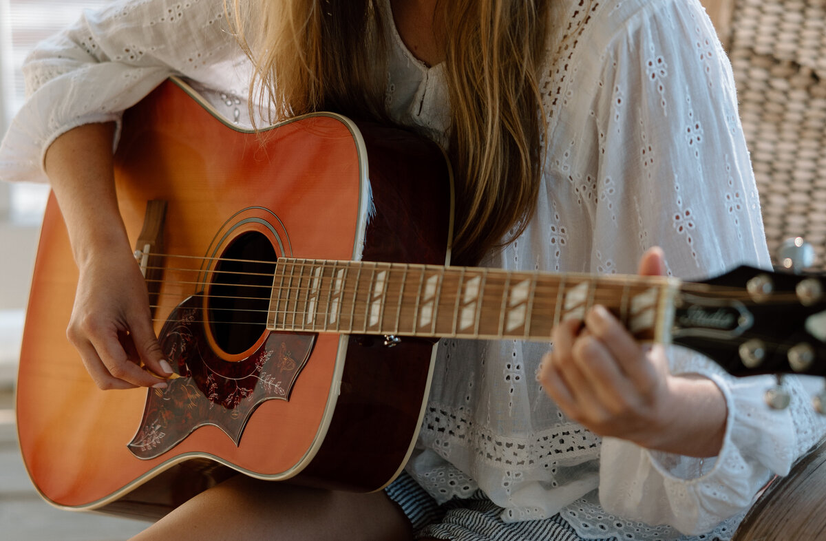 Senior photos at Edisto beach, senior sits on porch with a guitar