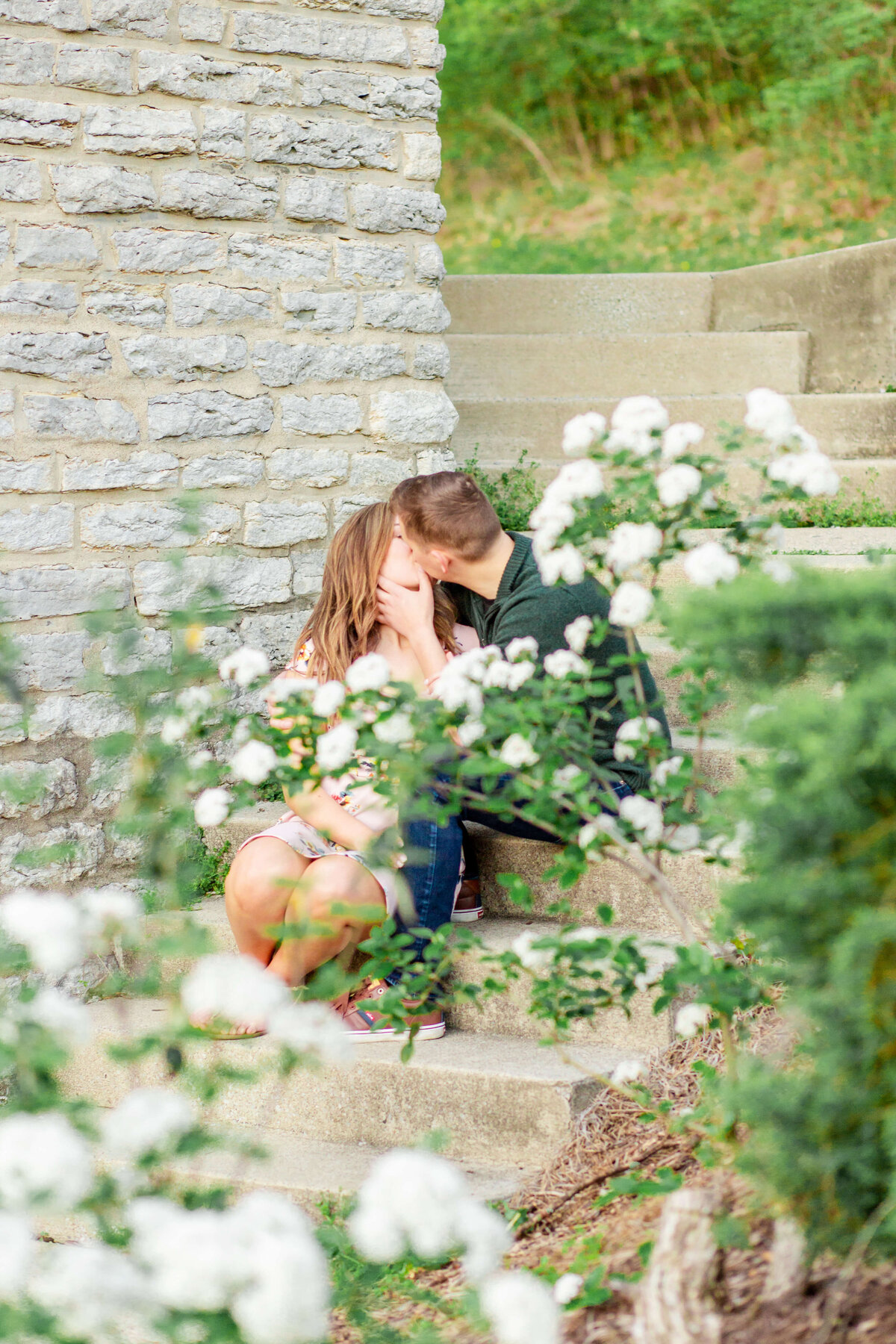 Engaged-couple-kissing-on-steps-outside