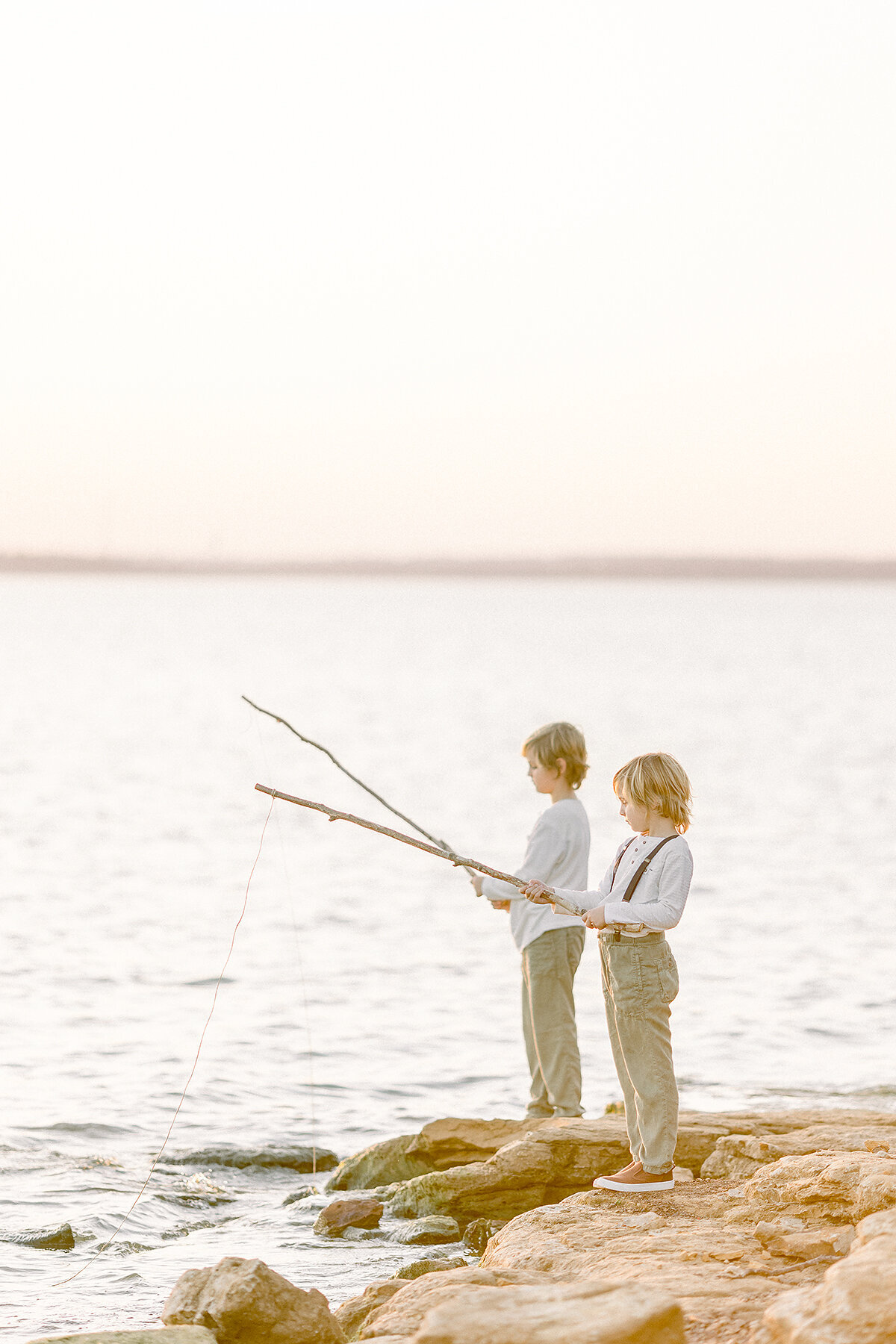 Two young brothers pretending to fish at a DFW lake for family photos.