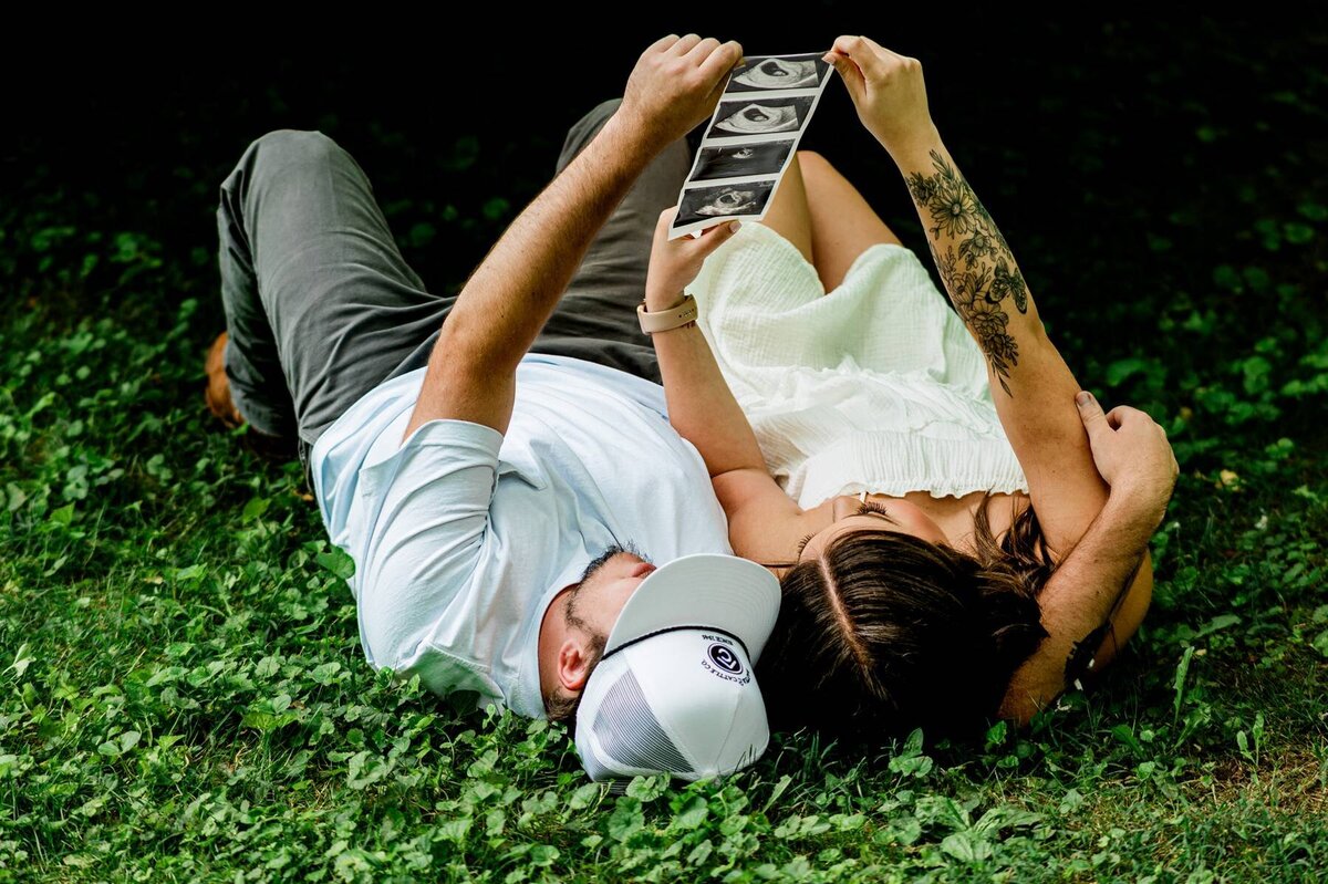 Maternity couple lying down and looking at ultrasound photos