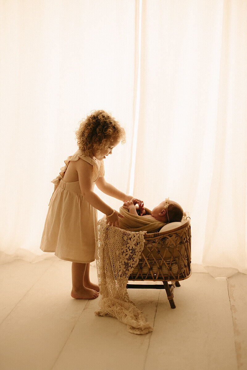 Nashville TN newborn photographer captures toddler playing with swaddled baby in studio