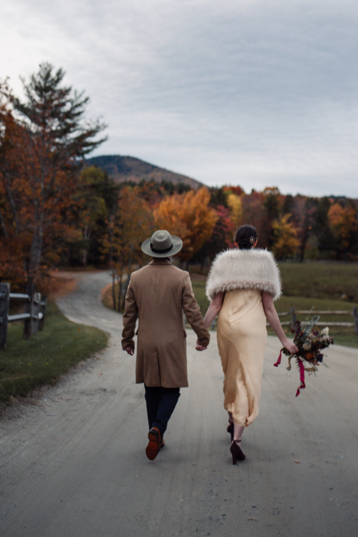 couple walks down dirt road for fall wedding