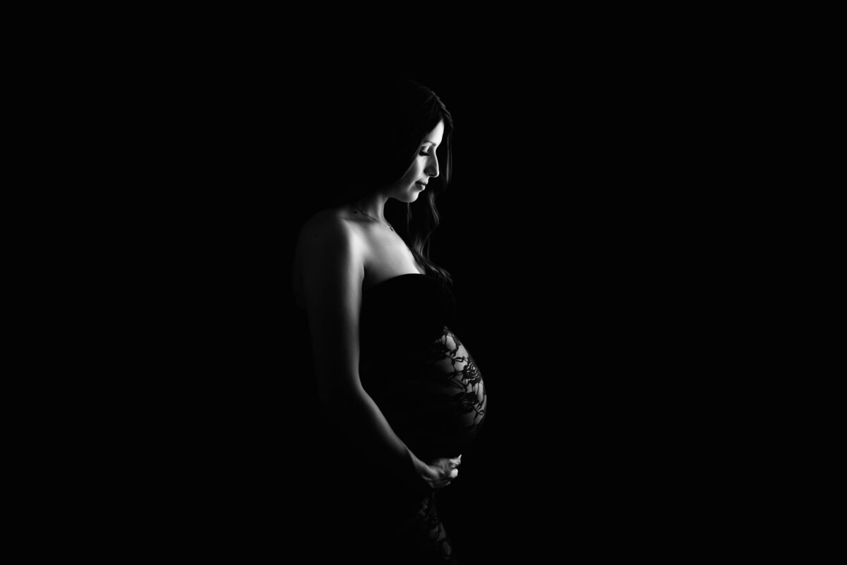 Black and white maternity photo with a black background