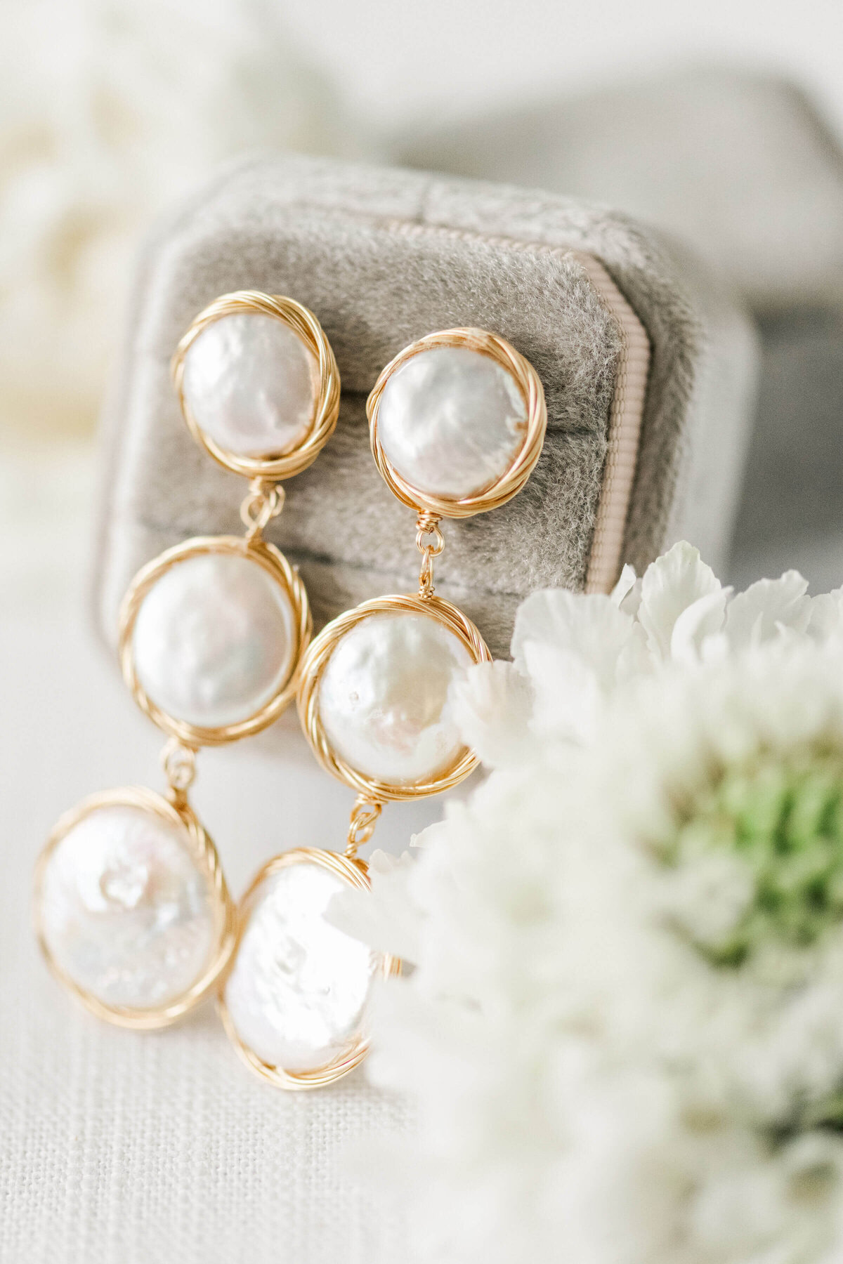 Bride gold and pearl earrings close up with white florals