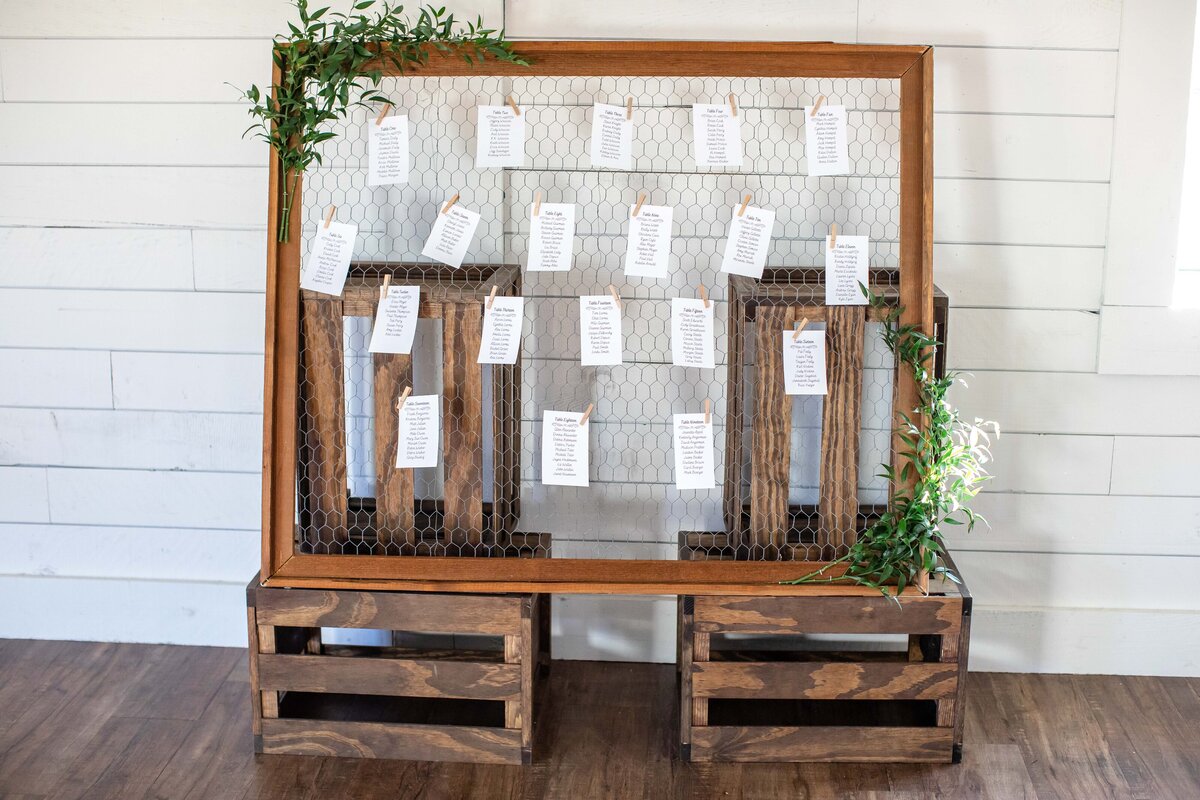 table seating chart on chicken wire with apple crate stand at wedding Morgan Creek Barn in Dripping Springs Texas by Firefly Photography