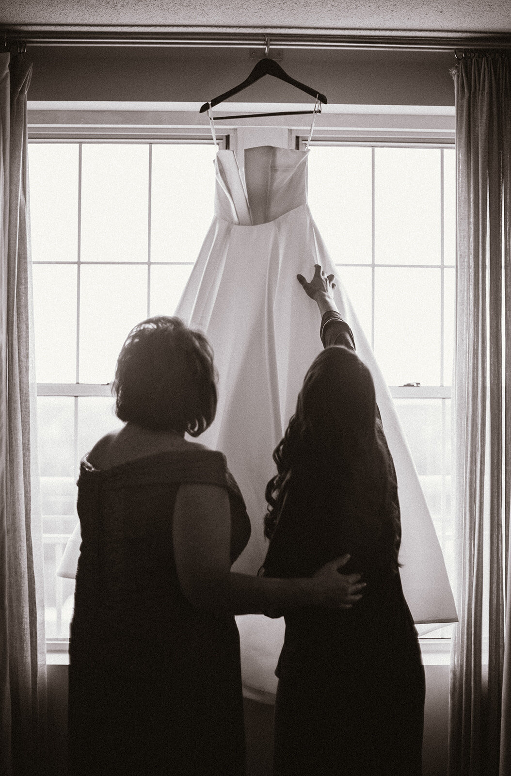 mother of the bride and her daughter share a moment looking at wedding dress