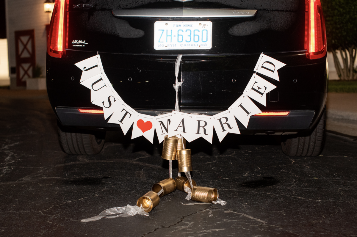 Spring wedding at WinMock at Kinderton, designed by Charming Carolina — back of the getaway car decorated with a Just Married sign and classic tin cans trailing behind.