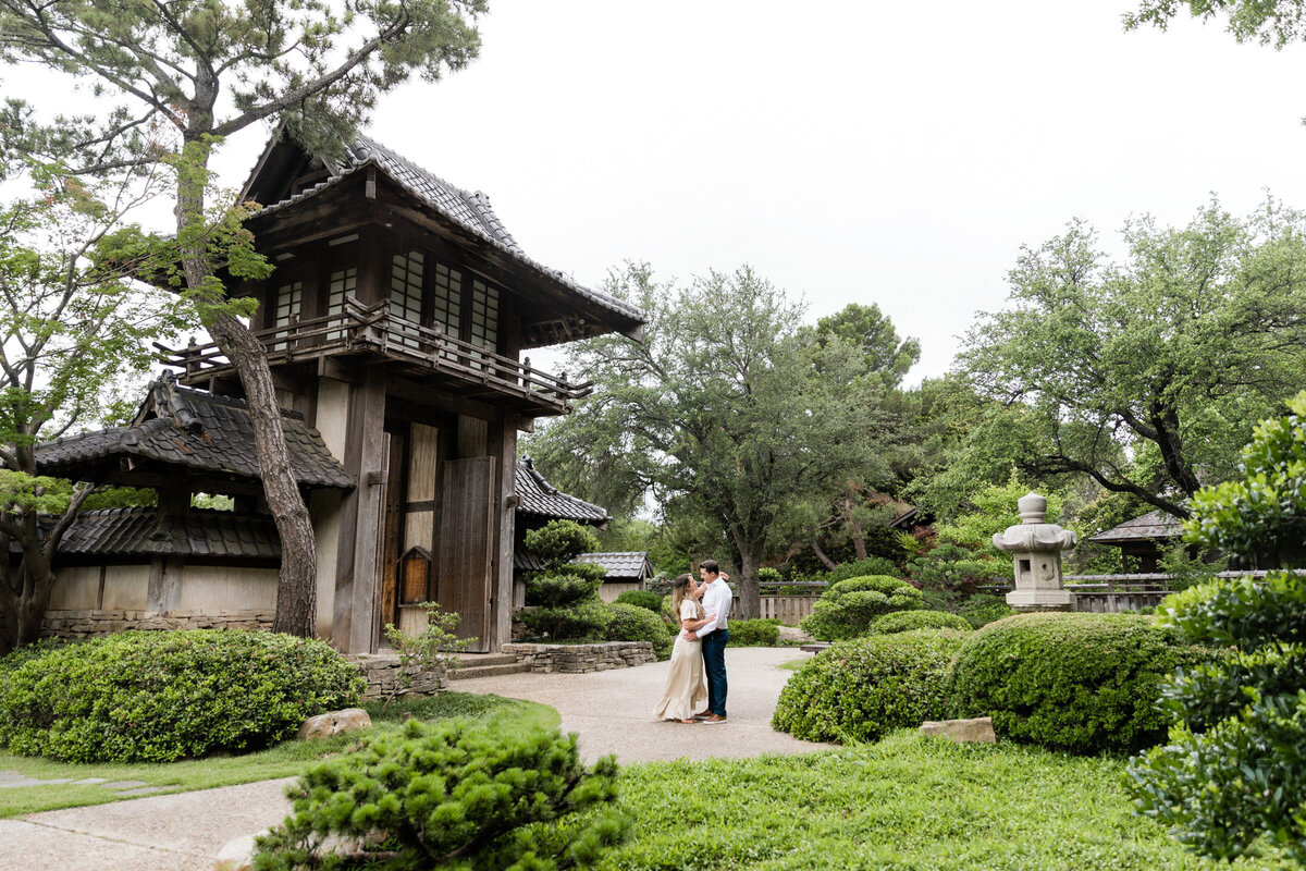 Couple in the Fort Worth Botanical Garden Japanese Garden during their engagement session, posed in front of the decorative gates