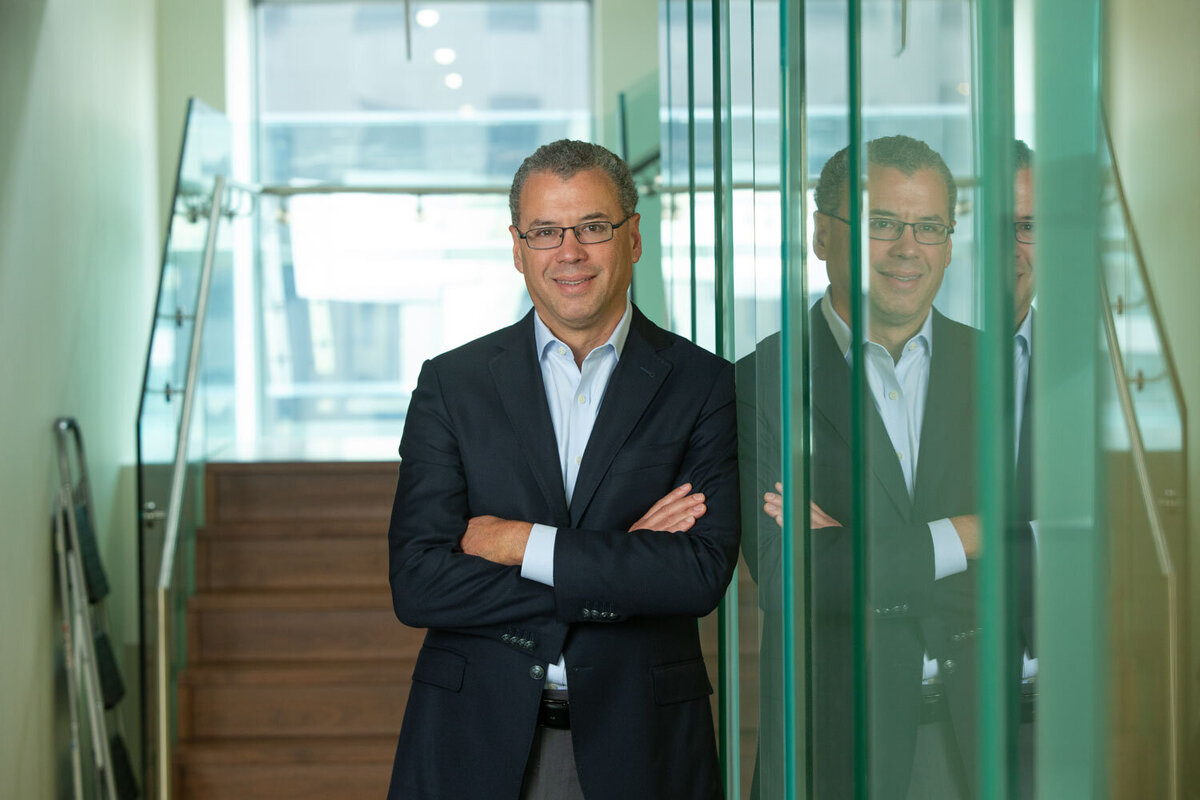 Man in suit standing next to glass wall with reflection