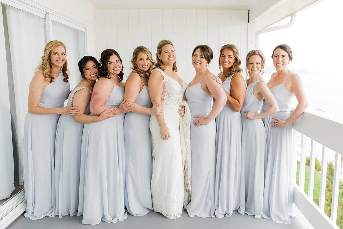 Bride on balcony with bridesmaids in pale blue dresses
