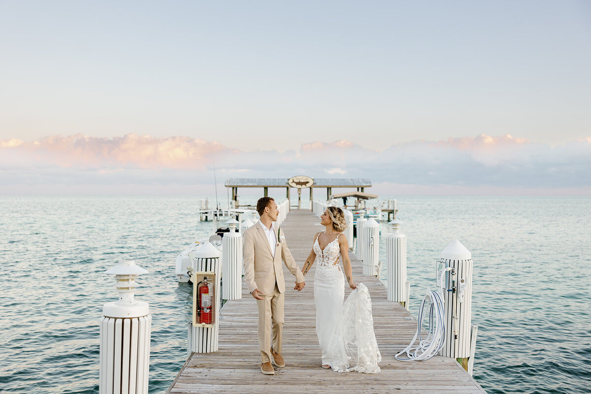 Ashley and Hunter hold hands as they stroll along the dock at sunset