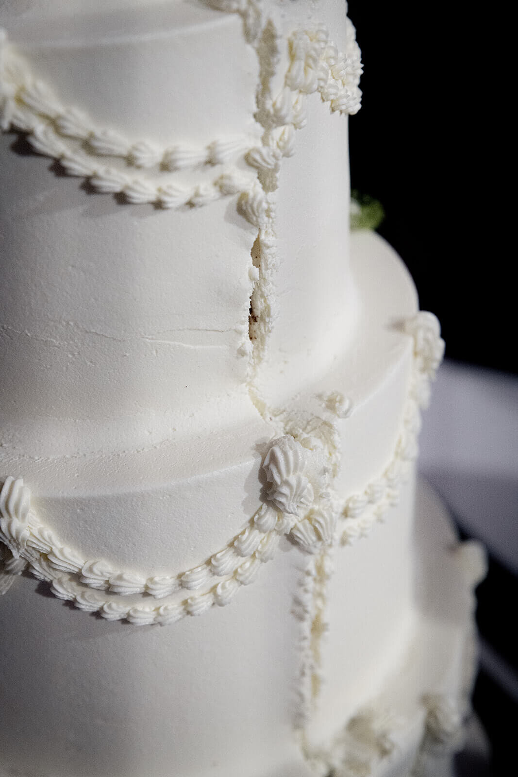 Three tiered wedding cake with a cut through the icing