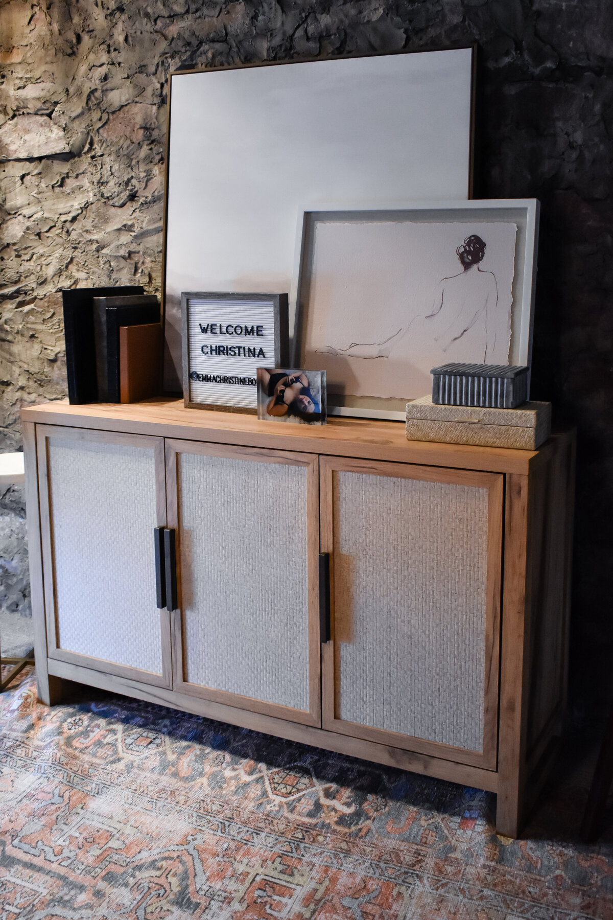 A large storage console sits in front of a textured stone wall