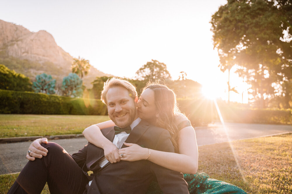 man and woman sitting on the grass embracing at sunset - Townsville Engagement Photography by Jamie Simmons