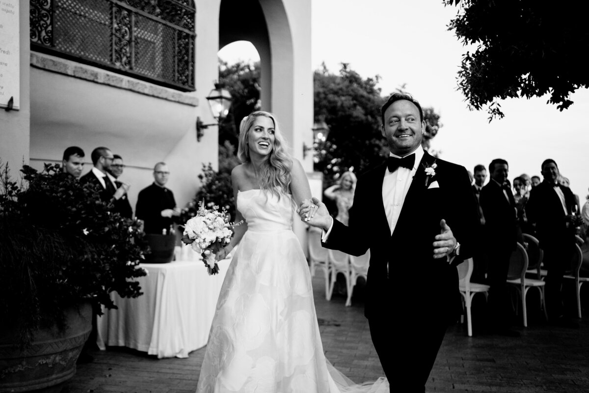 black and white image of a bride and groom walking down aisle after getting married
