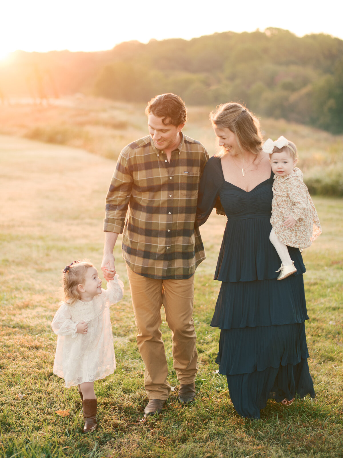 Family walks through a field at sunrise during a family session at the art museum. Image by Raleigh maternity photographer A.J. Dunlap Photography.
