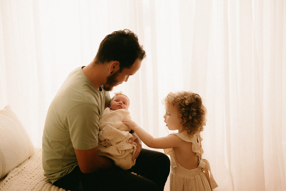 dad and sister admiring newborn during Nashville TN studio photo session