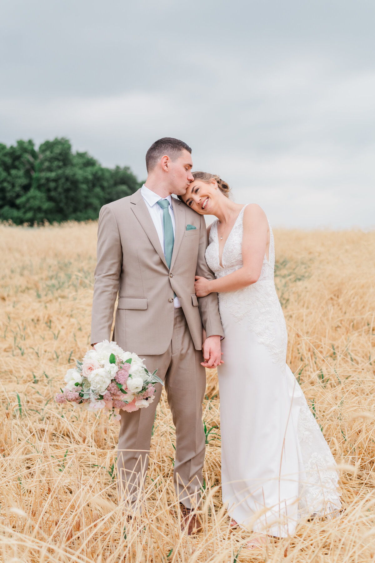 a happy bride and groom pose in a field of wheat at pine ridge farm in stewartstown pennsylvania