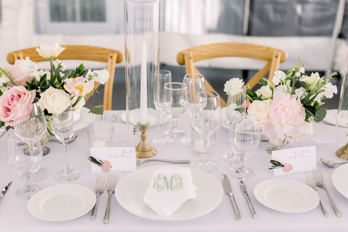 Table set with elegant dinnerware, pink and white flowers, and monogrammed napkins