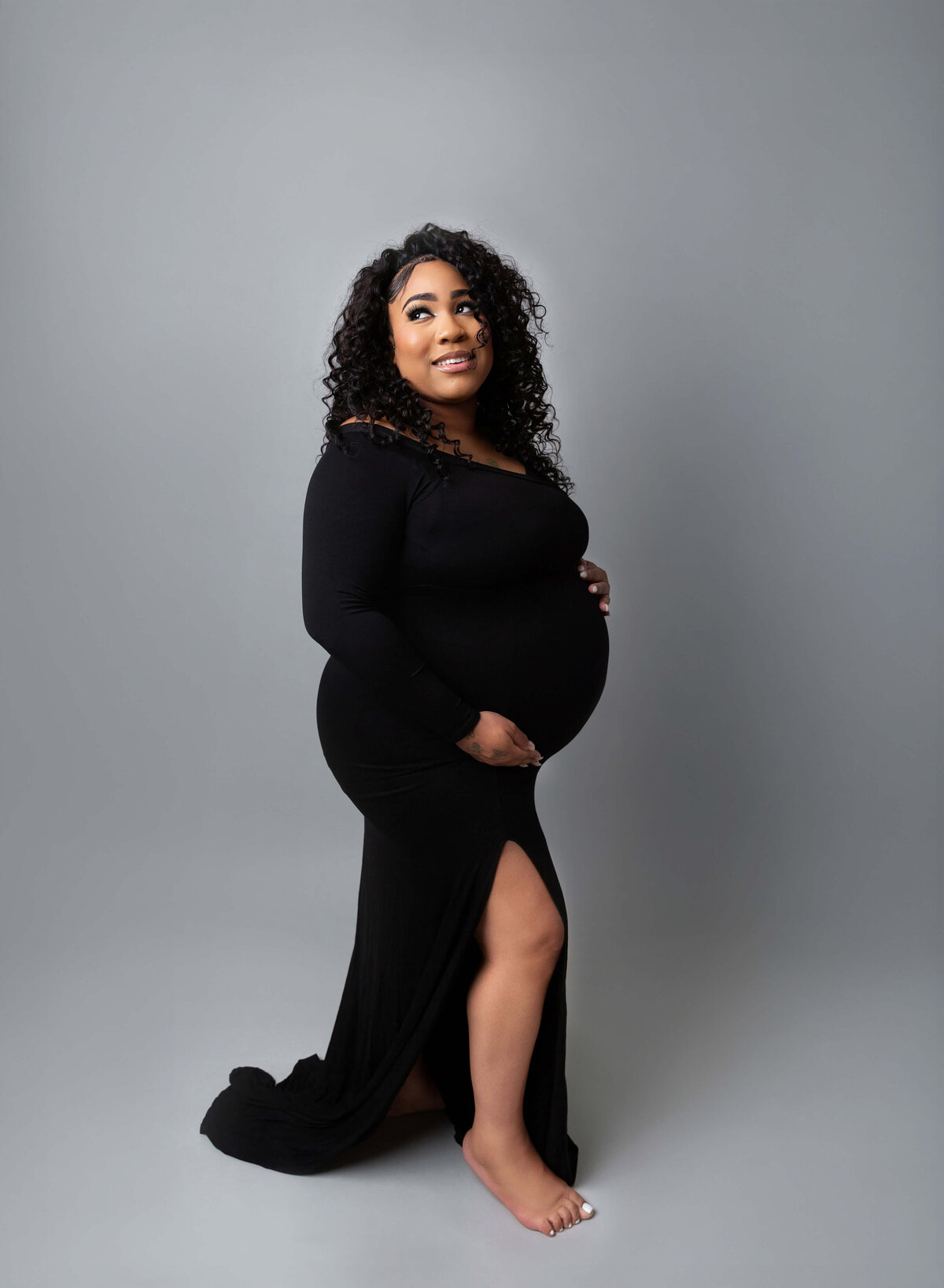 Expectant mother in a sleek black dress, beautifully captured during a NYC maternity photography session, highlighting the elegance and strength of pregnancy