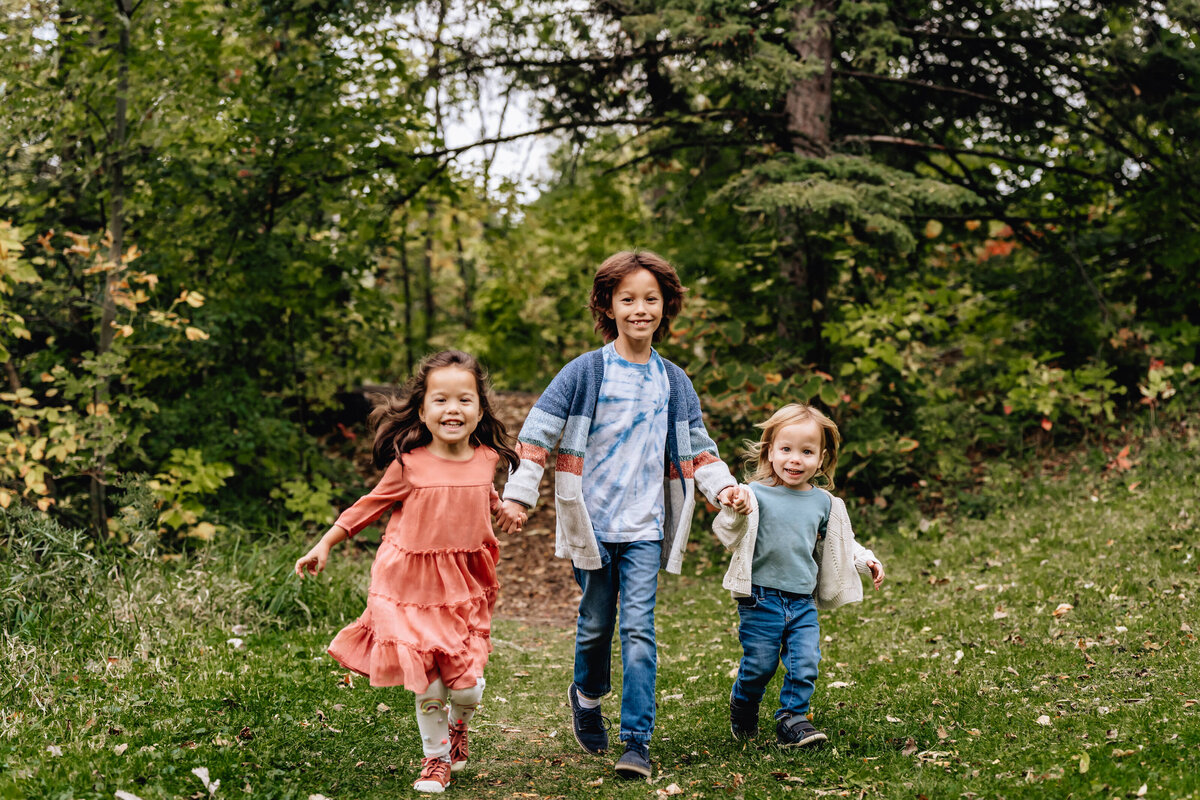 Three kids walk and have fun in the forest.