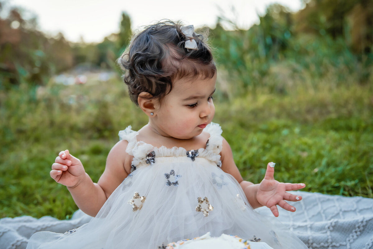 Little girl dressed in white doing a cake smash for her 1st birthday in Boonton NJ