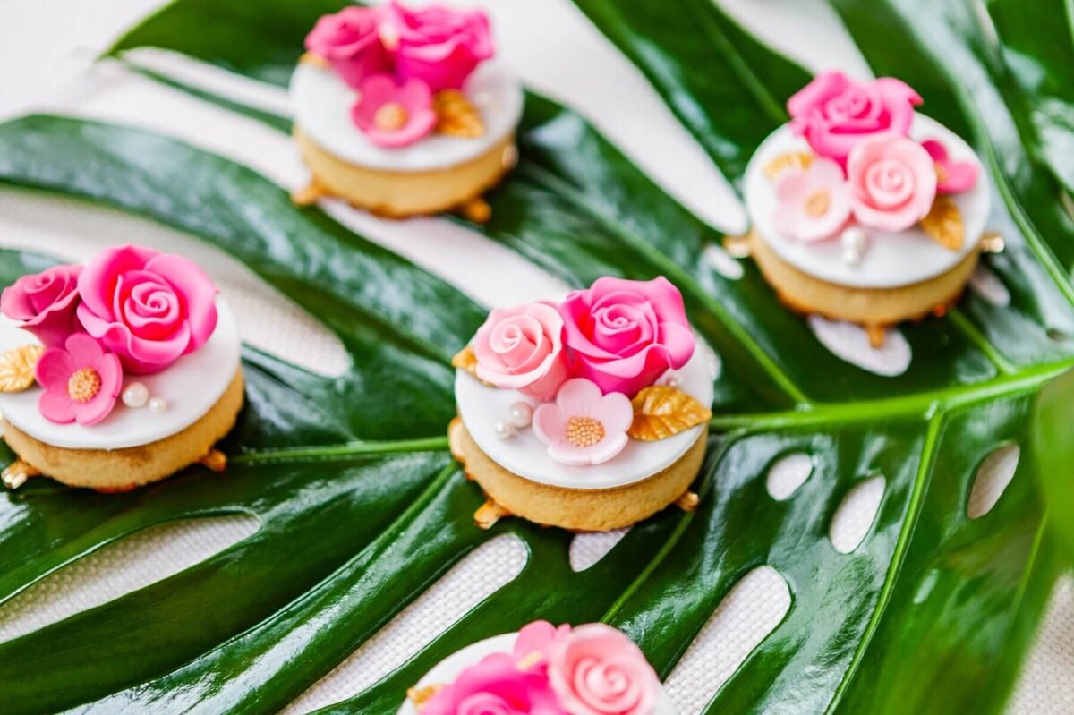Tropical leaf decorated with mini iced biscuits with pink sugar flowers