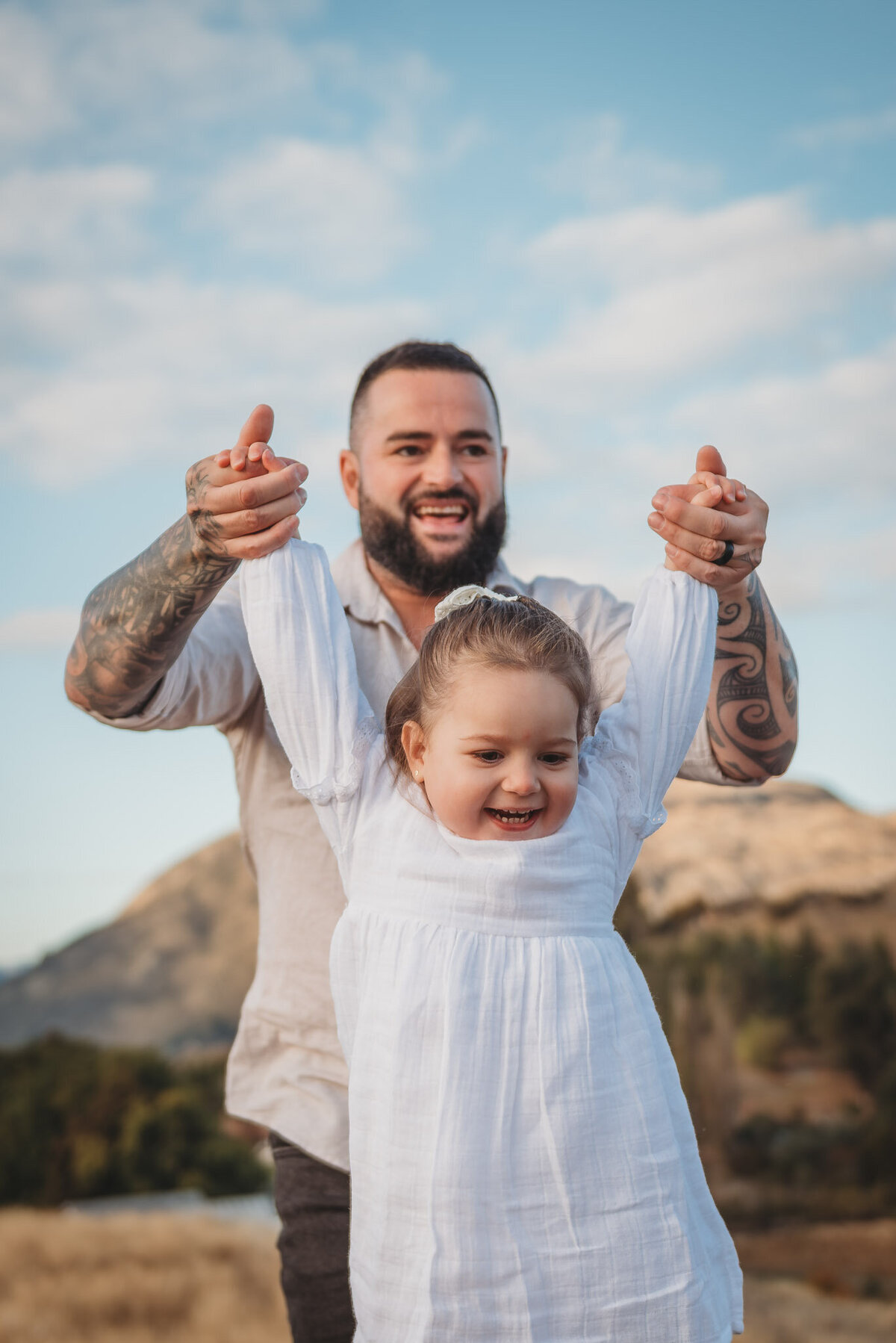 a dad playing with his daughter during their queenstown family photography session captured by Bie