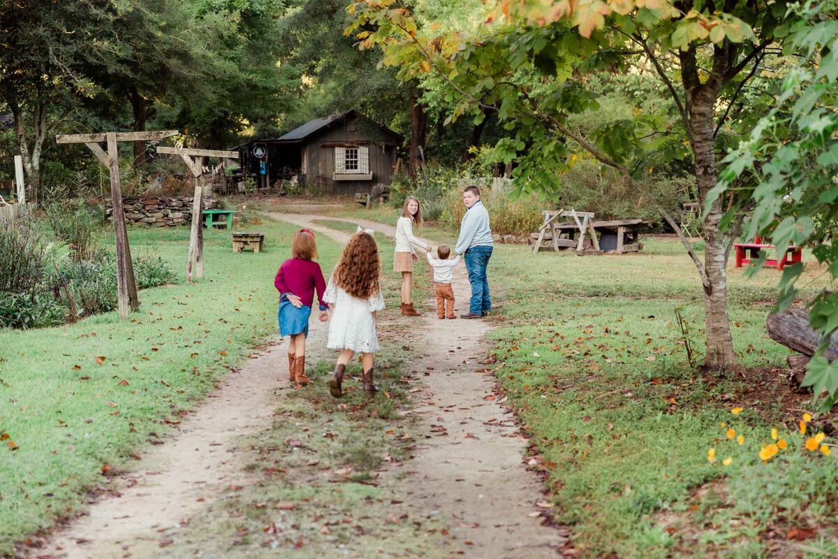 A moment captured with 5 cousins walking and running down a dirt road during their family session.